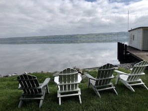 Une vue sur le lac, avec des fauteuils Adirondack et une jetée qui s’avance dans l’eau.