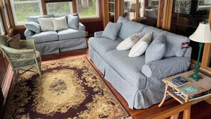 A cozy living room with two sofas, a wicker chair, a patterned rug, and a small table with a lamp. - Cayuga Lake Cottage near Ithaca, Taughannock Falls State Park and Trumansburg, N (Trumansburg)