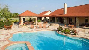 A swimming pool with a patio area, outdoor seating, and a covered section.