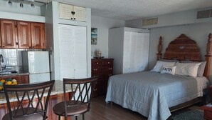 A bedroom with a bed, a nightstand, a wooden headboard, and a window. - 24 gated security studio apartment,  Seawind on the bay Freeport Mobay (Montego Bay)