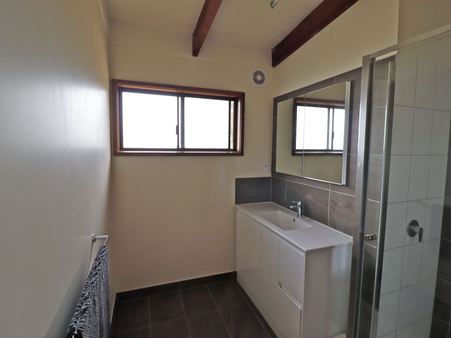 Ein Badezimmer mit Fenster, Waschbecken, Spiegel und Dusche.
