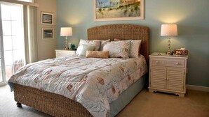 A bedroom with a large bed, two bedside tables, a wicker headboard, and a painting on the wall. - Spacious and Well Appointed Three Bedroom, Two Bath Condo situated just outside the Town of Lewes Delaware (Lewes)