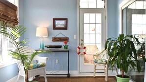 A room with a potted plant, a chair, a lamp, and a door with a life preserver decoration. - Spacious and Well Appointed Three Bedroom, Two Bath Condo situated just outside the Town of Lewes Delaware (Lewes)