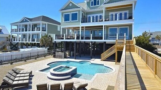 A large, multi-story beachfront house with a swimming pool and outdoor seating area. - Luxurious Oceanfront Home: Pool, SPA, & Movie Theater (Murrells Inlet)