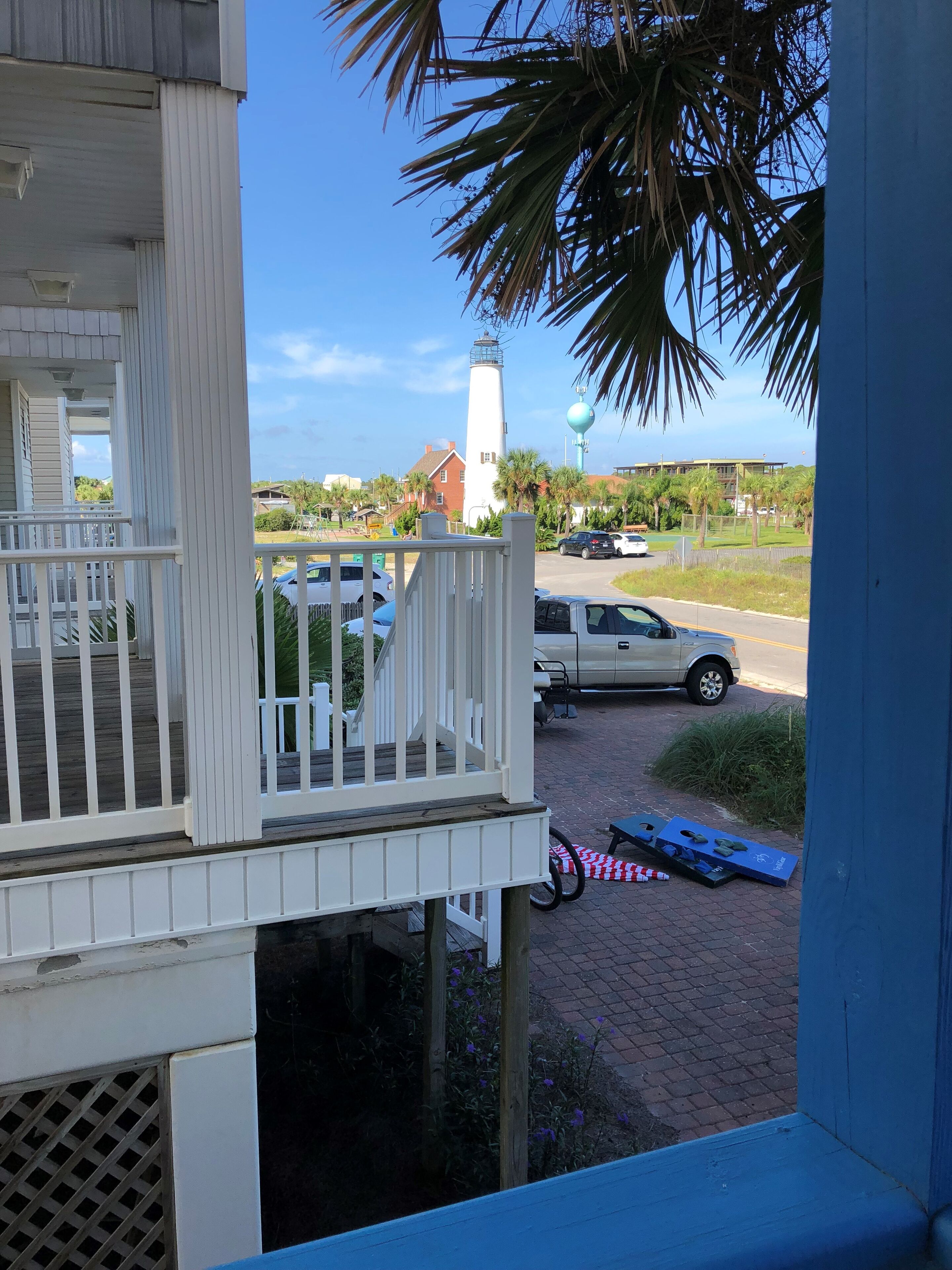 A balcony with a view of a parking area, a lighthouse, and a building with a blue exterior.