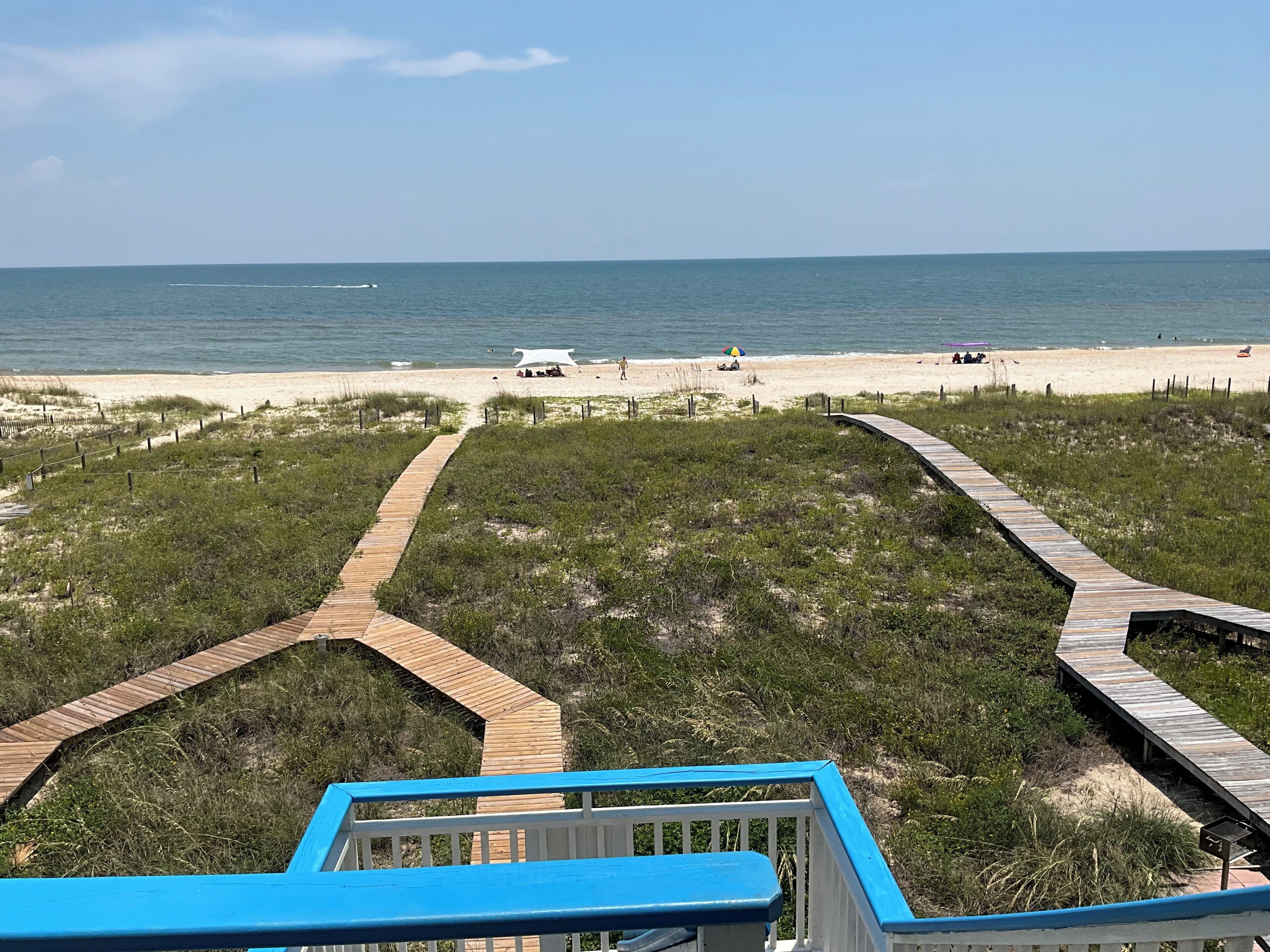 A beach with wooden boardwalks leading to the shore, a clear sky, and the ocean in the background.