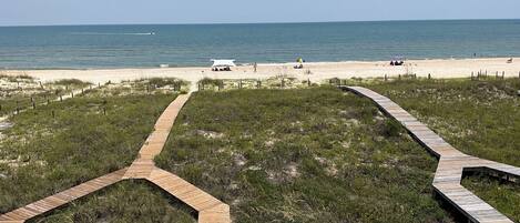 A beach with wooden boardwalks leading to the shore, a clear sky, and the ocean in the background.