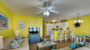 A living room with a sofa, TV, and a dining area with chairs and a table.