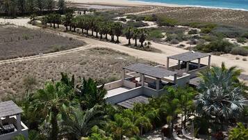 A resort with a pool, solar panels, and a view of the beach.