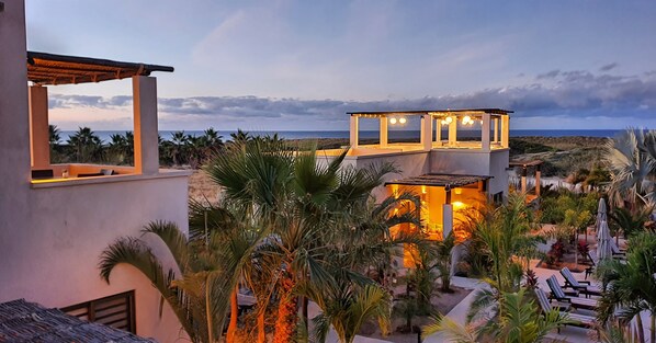 A resort with a pool area, lounge chairs, and a view of the ocean.
