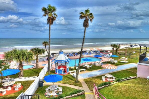 Relax by the pool surrounded by palm trees and beach umbrellas, with a gazebo and lounge chairs at your disposal.