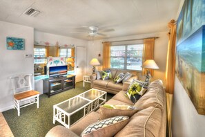 Relax in this inviting living room with a sofa set, television, and ceiling fan.