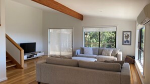 Ein großzügiges Wohnzimmer mit einer großen Couch, einem Fernseher und einer Treppe.