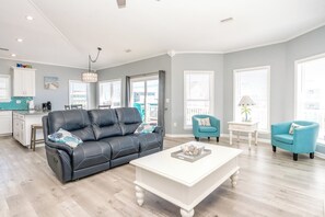 A modern living room with a black leather sofa, a white coffee table, and teal armchairs. - Finally Beachin' - Great 4 BR Home - Ocean View & Easy Beach Access!! (Topsail Beach)