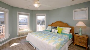 Ein Schlafzimmer mit Bett, Deckenventilator, Nachttisch und Fenster.