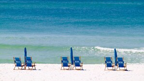 A beach with four blue beach chairs and umbrellas labeled "Sea View." - Gulf Front Sea Oats 303 with Rocker Recliner, Comfy beds and Beach Service!  (Fort Walton Beach)