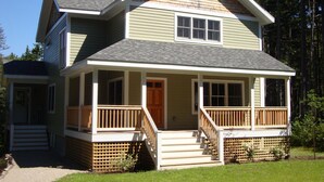 A two-story house with a front porch, a small staircase, and a wooden fence. - Gorgeous Newer Home on Mt. Desert Island, Minutes to Acadia (Bass Harbor)