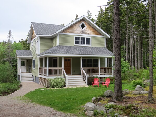 A two-story house with a porch, a front door, and a small front yard with a gravel path leading to the door.