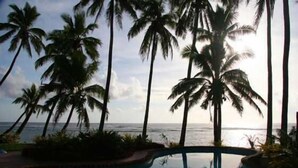 A pool area with palm trees and a view of the ocean. - Heritage, Pool and AirCon (Arorangi)