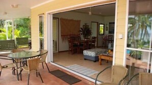 A covered patio with a glass table and chairs, a sliding glass door leading to an interior dining area with a table and chairs. - Heritage, Pool and AirCon (Arorangi)