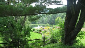 Un exuberante jardín con un estanque, rodeado de diversas plantas y una valla de madera.