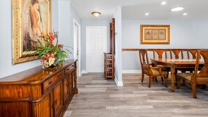 A dining area with a wooden table and chairs, a cabinet with a vase of flowers, and a painting on the wall. - 6bdr/4bath tropical paradise with heated pool and lanai, 1 mile from the beach (Naples)