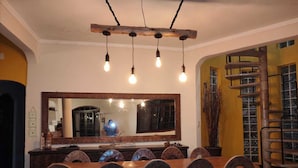 A dining area with a wooden table and chairs, a large mirror, and a unique spiral staircase.