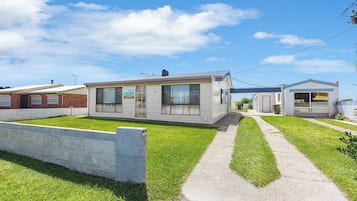A row of mobile homes with a grassy lawn and concrete pathway.