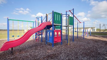 A playground with a red slide, climbing structures, and a green platform.