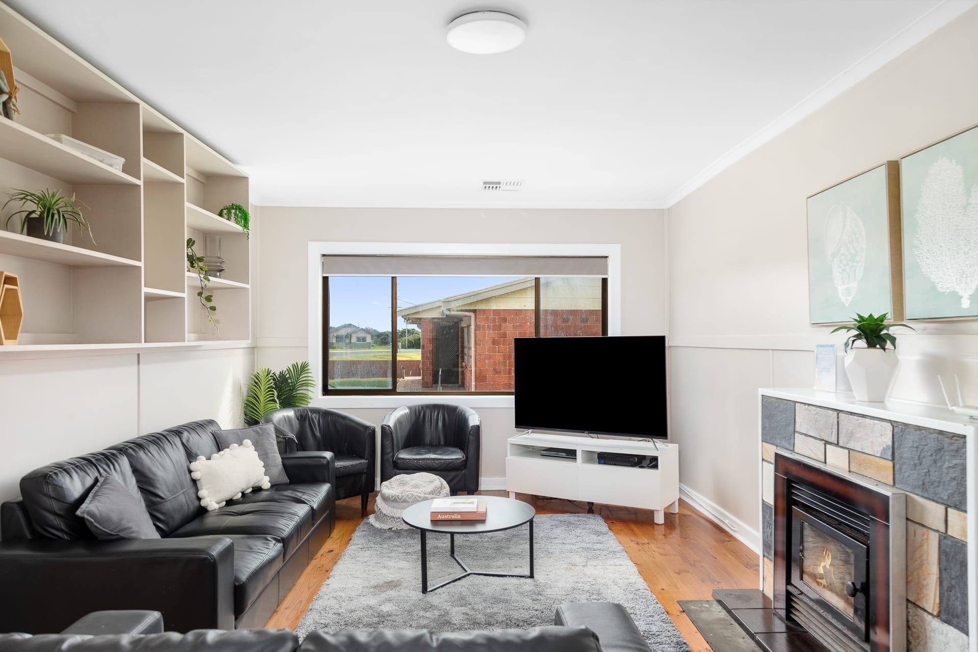 A modern living room with a fireplace, a flat-screen TV, and a large window.