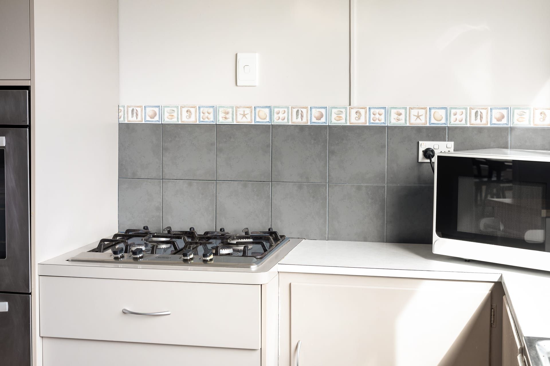 A kitchen with a gas stove, oven, and a tiled backsplash.
