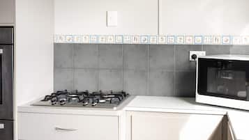 Eine Küche mit Gasherd, Backofen und einer gefliesten Spritzschutzwand.