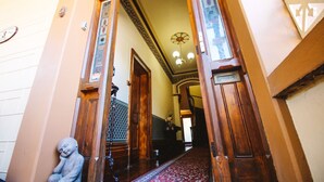 A hallway with wooden doors, a patterned wall, and a chandelier. - Hindmarsh House on College | Steps to Glenelg Beach, Cafes & Jetty Road (Glenelg)
