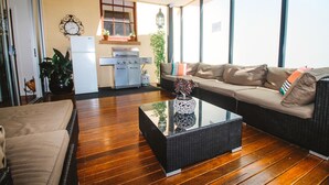 A spacious living area with a sofa, a coffee table, and a kitchen in the background. - Hindmarsh House on College | Steps to Glenelg Beach, Cafes & Jetty Road (Glenelg)