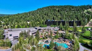 Un resort con piscina, varias edificaciones y un paisaje montañoso cubierto de bosque.