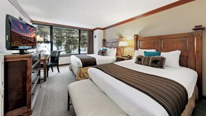 Habitación de hotel con dos camas, televisión, escritorio y una silla.