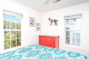 Een slaapkamer met een bed, een rode kapstok en twee foto's in lijsten aan de muur.