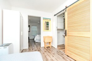 A bedroom with a bed, a wooden wardrobe, and a bathroom visible through an open door.