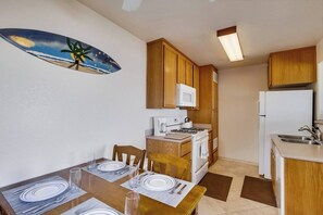A compact kitchen with wooden cabinets, a microwave, stove, and a refrigerator.