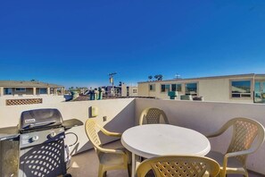 Terraço no telhado com churrasqueira, uma mesa redonda e quatro cadeiras.