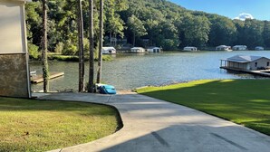 A lakeside property with a dock, a grassy area, and a building with a garage. - WATERFRONT kayaks, paddleboat Beautiful Smokey Mountain Views, close to shopping (Guntersville)