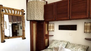Een slaapkamer met een bed, een spiegel, houten kasten en een wandplank.