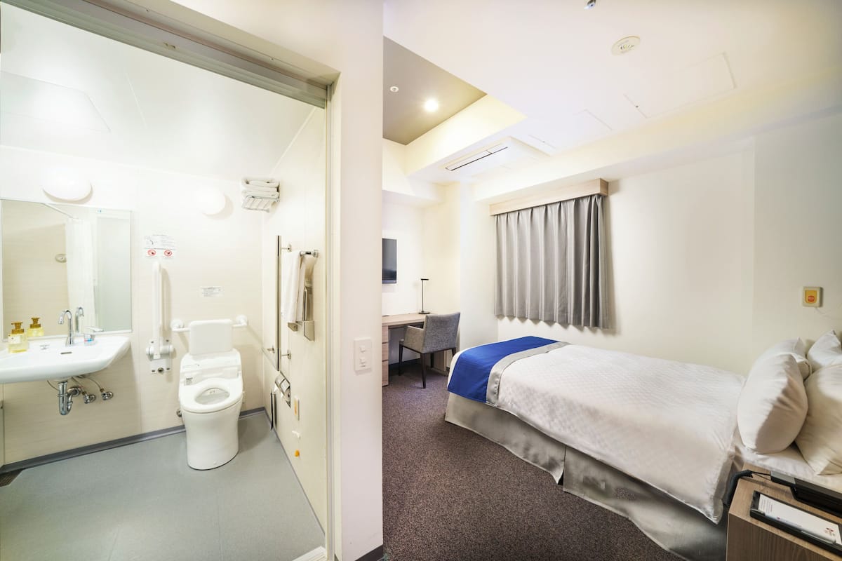 Een hotelkamer met een badkamer, een bed, een bureau en een stoel.