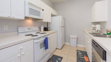 A modern kitchen with white cabinetry, a built-in microwave, a stove, a refrigerator, and a dishwasher.