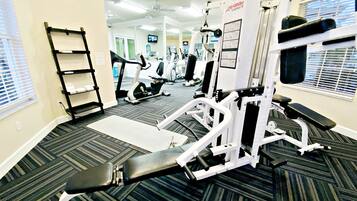 Een sportschool met diverse fitnessapparaten, een loopband en een spiegel die de ruimte weerspiegelt.