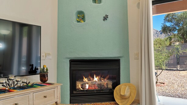 Ein Wohnzimmer mit Kamin, Fernseher und Blick ins Freie.