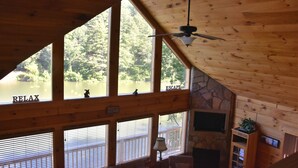 A cabin with large windows overlooking a lake, a ceiling fan, and a fireplace. - MTN CABIN LAKEFRONT,CANOE/3 KAYAKS,POOL TABLE,DOCK,FIRE PIT, FIREPLACE,JACUZZI (Butler)