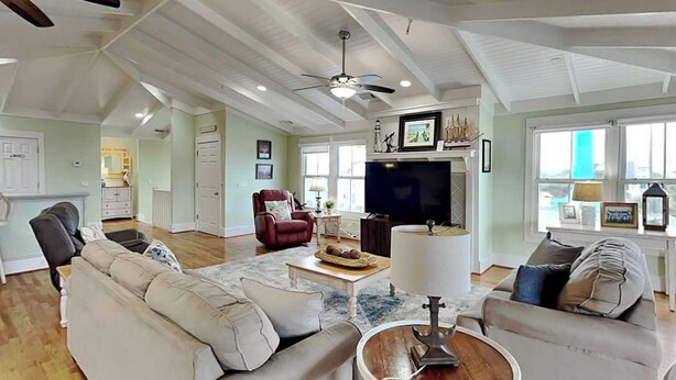 A spacious living room with a high ceiling, a fireplace, a television, and a dining area.