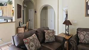 A living room with a brown leather sofa, patterned throw pillows, a wooden side table with a lamp, and a painting on the wall. - Sedona Get-Away Sleeps  6 (Sedona)