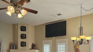 A living room with a fireplace, a ceiling fan, a dining table with chairs, and a television mounted on the wall. - Sedona Get-Away Sleeps  6 (Sedona)